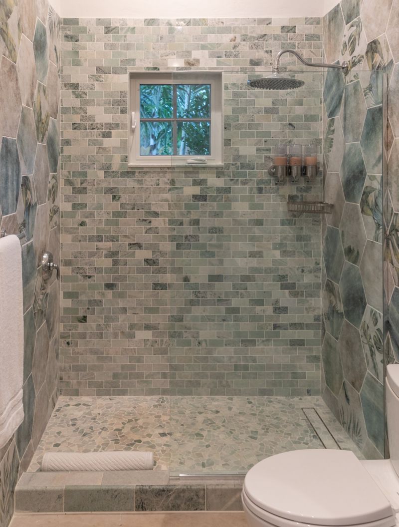 A bathroom in Harbour Island with a green marble tile shower and a pebble stone floor.