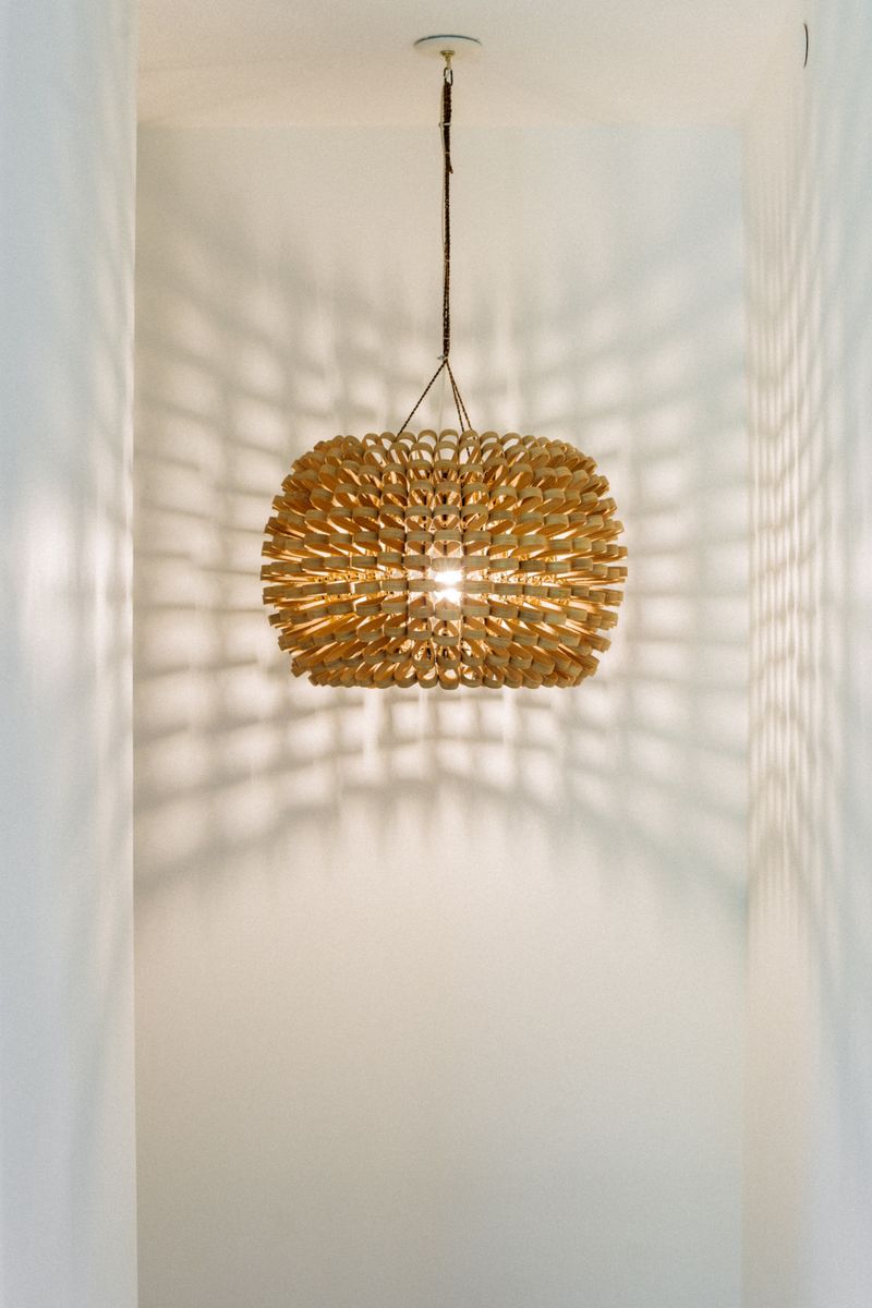 A woven rattan pendant light hanging in a white hallway in Johnston.