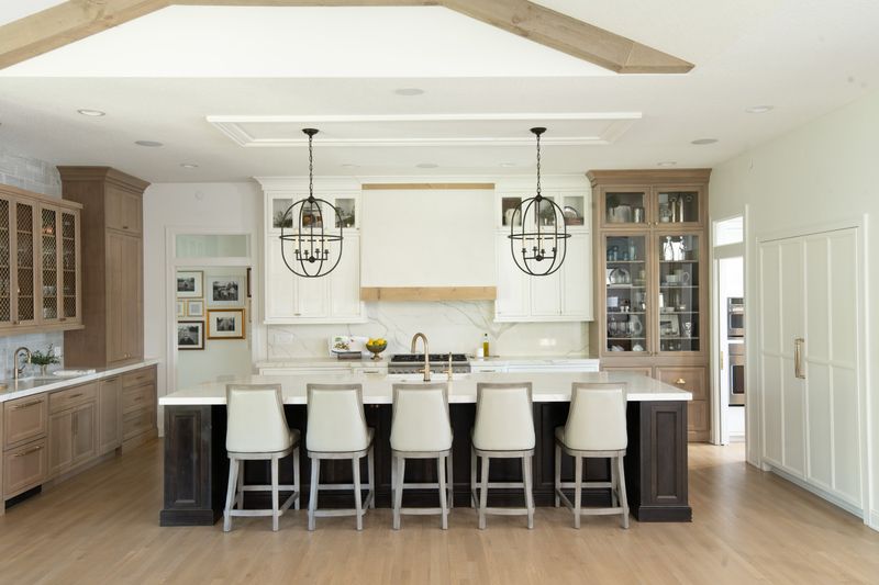 A white kitchen in Johnston with a white oak trimmed hood over the range and a marble backsplash.