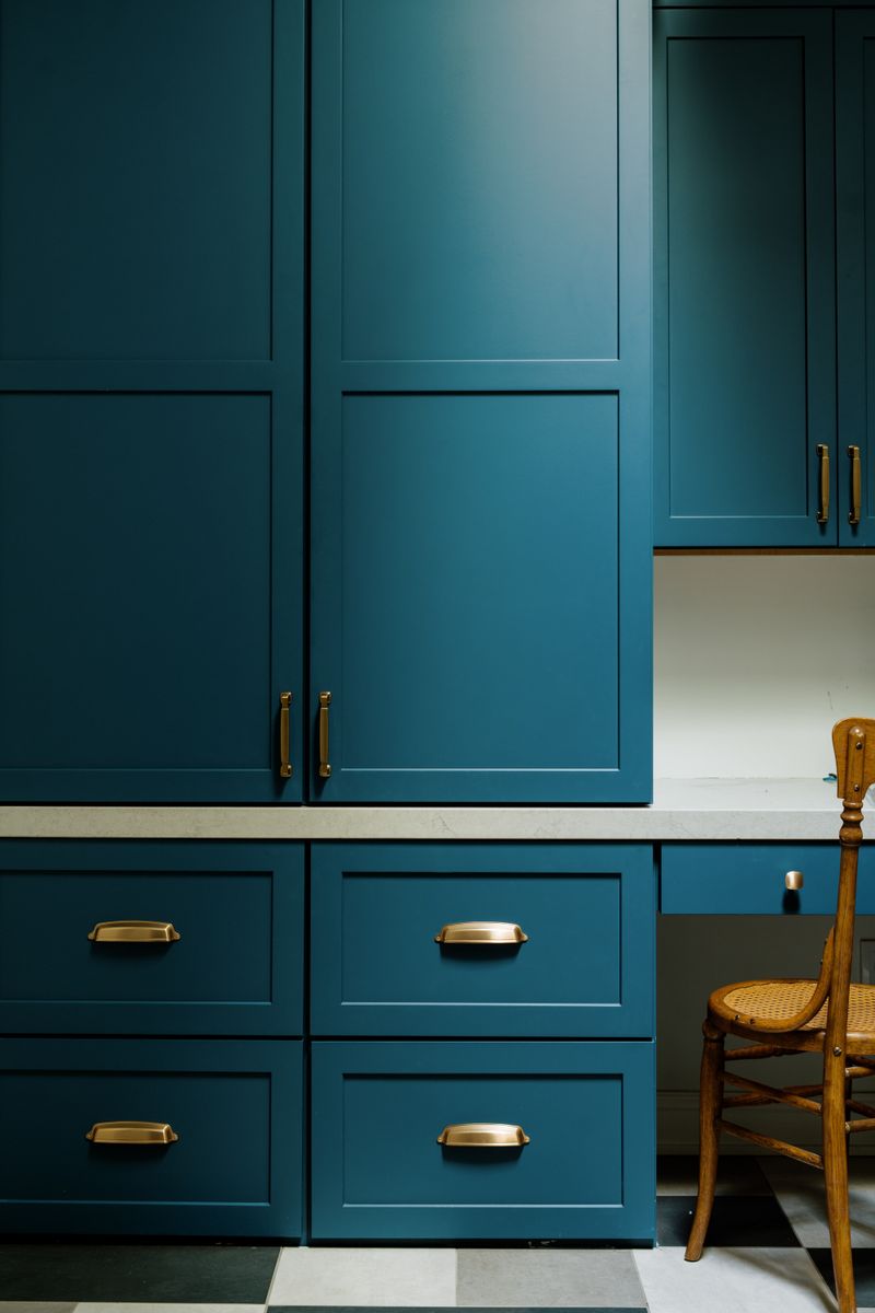 A laundry room in Johnston with teal shaker cabinets, brass cup pulls and a light quartz counter.
