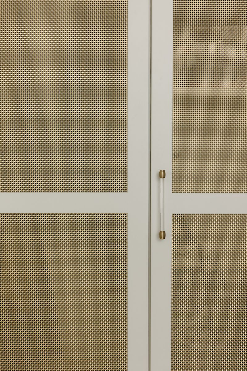 Greige cabinetry in West Des Moines with brass mesh door panels and a slim acrylic and brass pull.