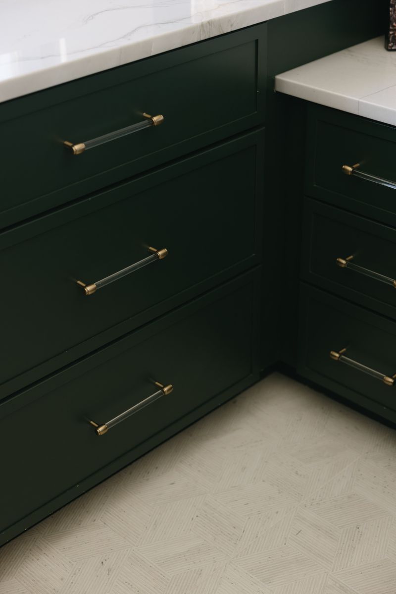 Dark green cabinets in West Des Moines with acrylic and brass pulls under a white marble counter.