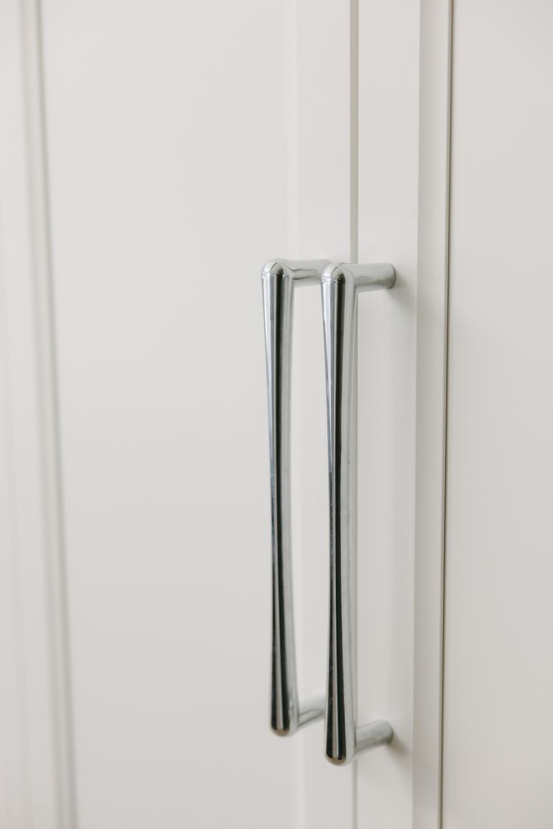 Polished chrome bar pulls on white kitchen cabinet doors in West Des Moines.
