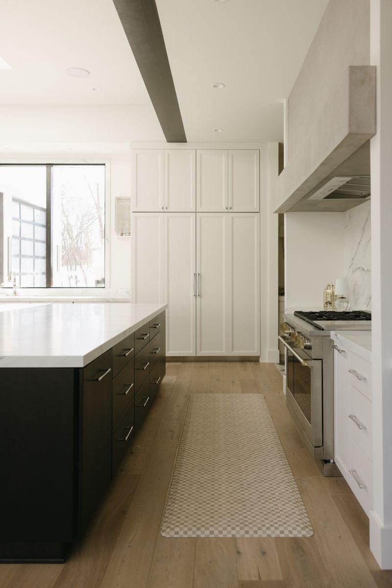 A white kitchen in West Des Moines with a plaster hood over the range and a dark island topped in marble.