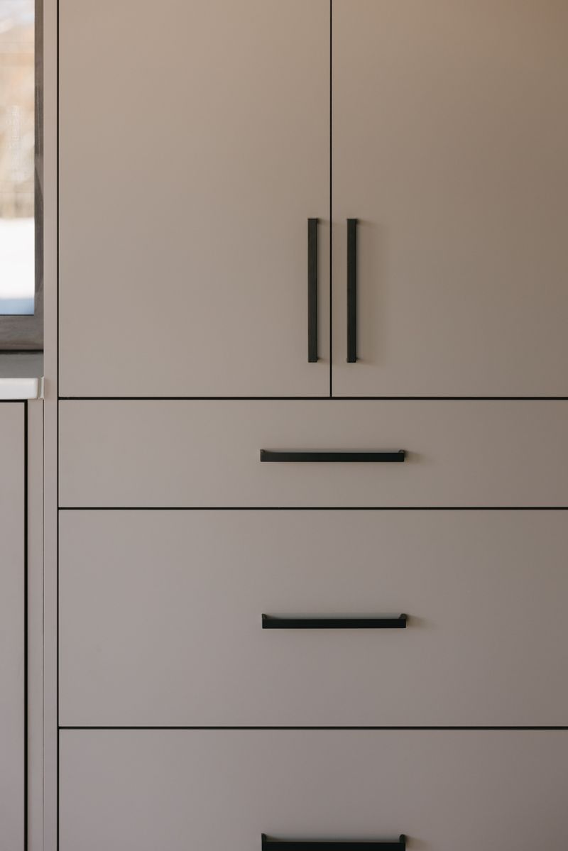 Flat panel greige kitchen cabinets in West Des Moines with long matte black bar pulls.
