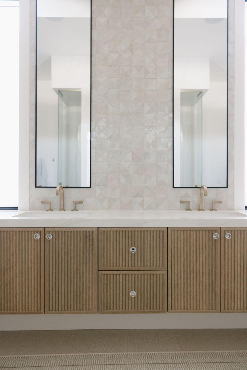 A primary bath in West Des Moines with a fluted white oak double vanity under a cream tile wall.