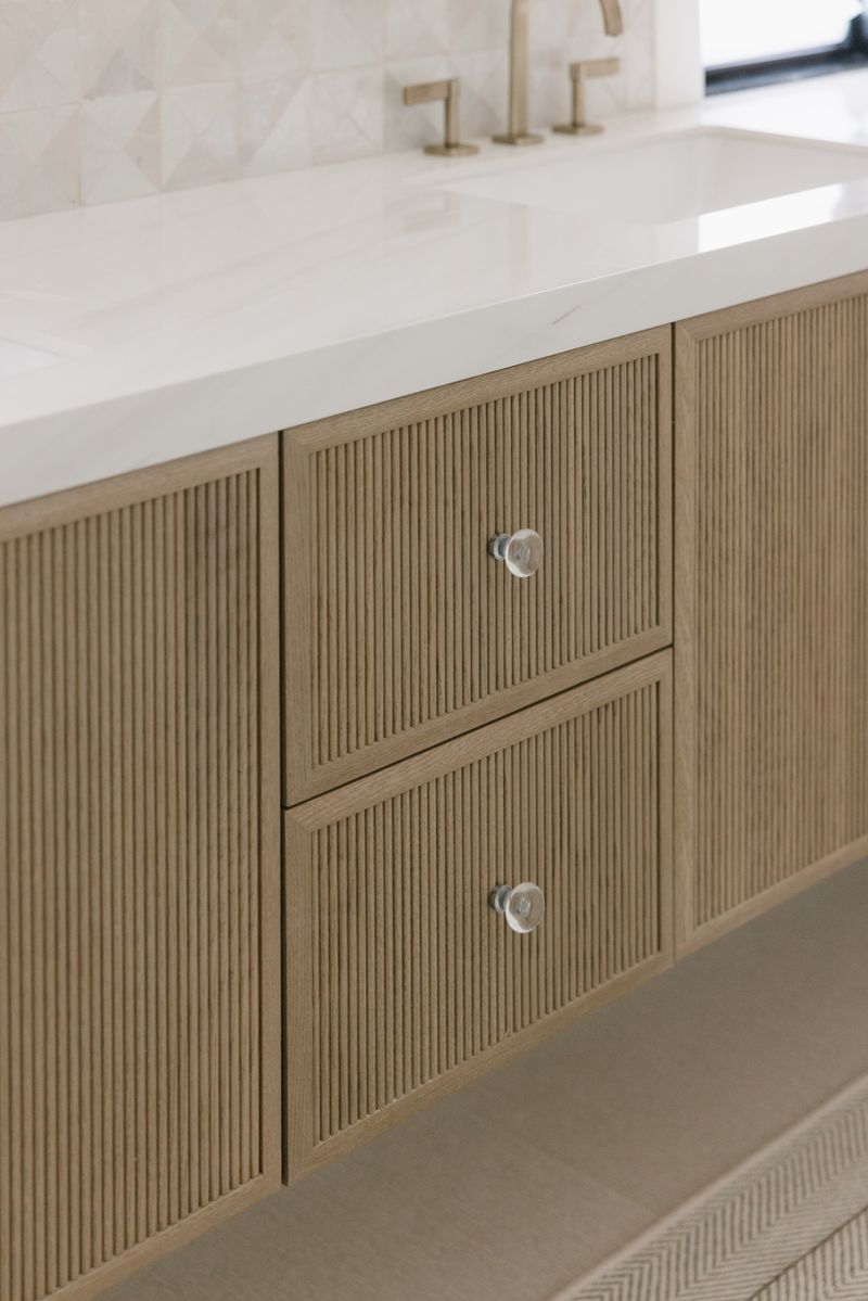A primary bath in West Des Moines with a fluted white oak vanity under a white marble counter.