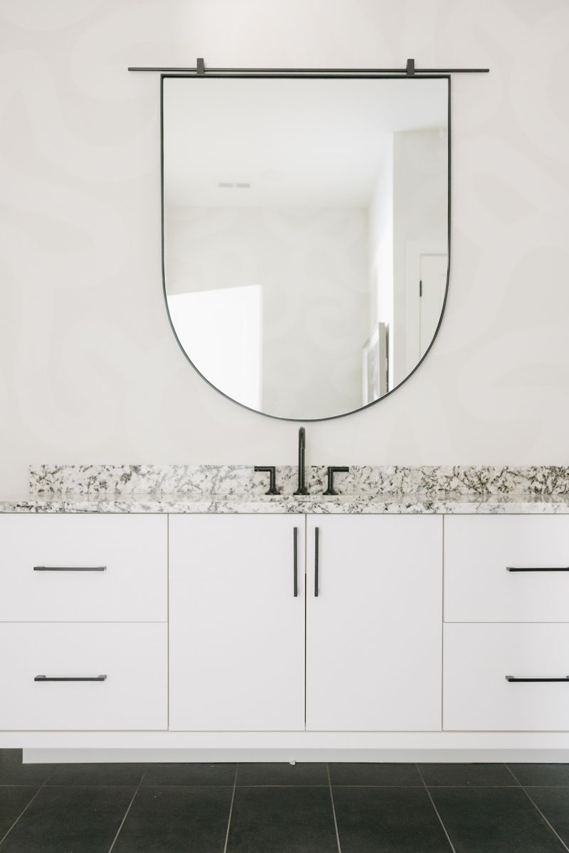 A primary bath in West Des Moines with a speckled granite counter on a flat white vanity, over dark slate tile.