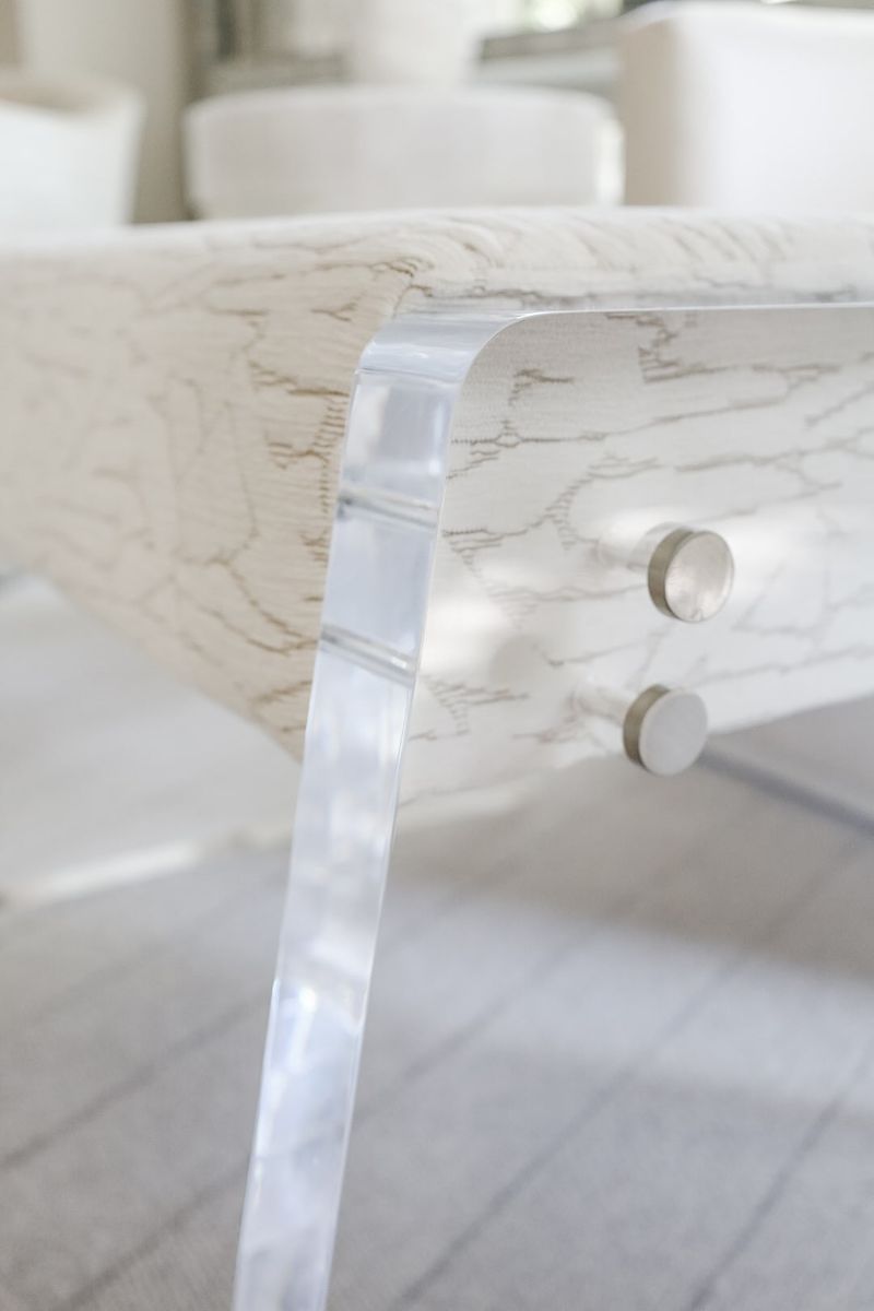 A whitewashed oak desk in Clive with a clear acrylic leg and round nickel drawer pulls.
