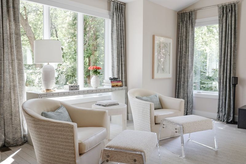 A cream living room in Clive with textured barrel chairs facing a mirrored console under the window.