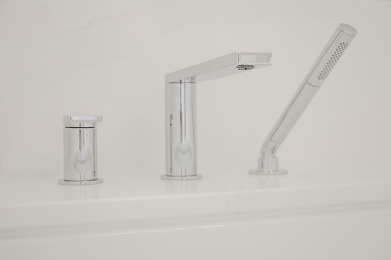 A primary bath in Clive with a chrome deck mounted tub filler and handheld sprayer on a white quartz surround.