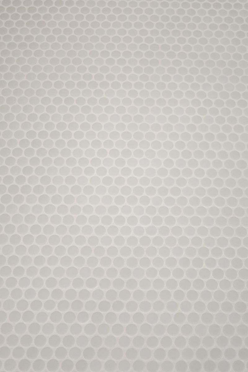 White penny round tile in Clive, set close together with matching pale grout for a soft matte finish.
