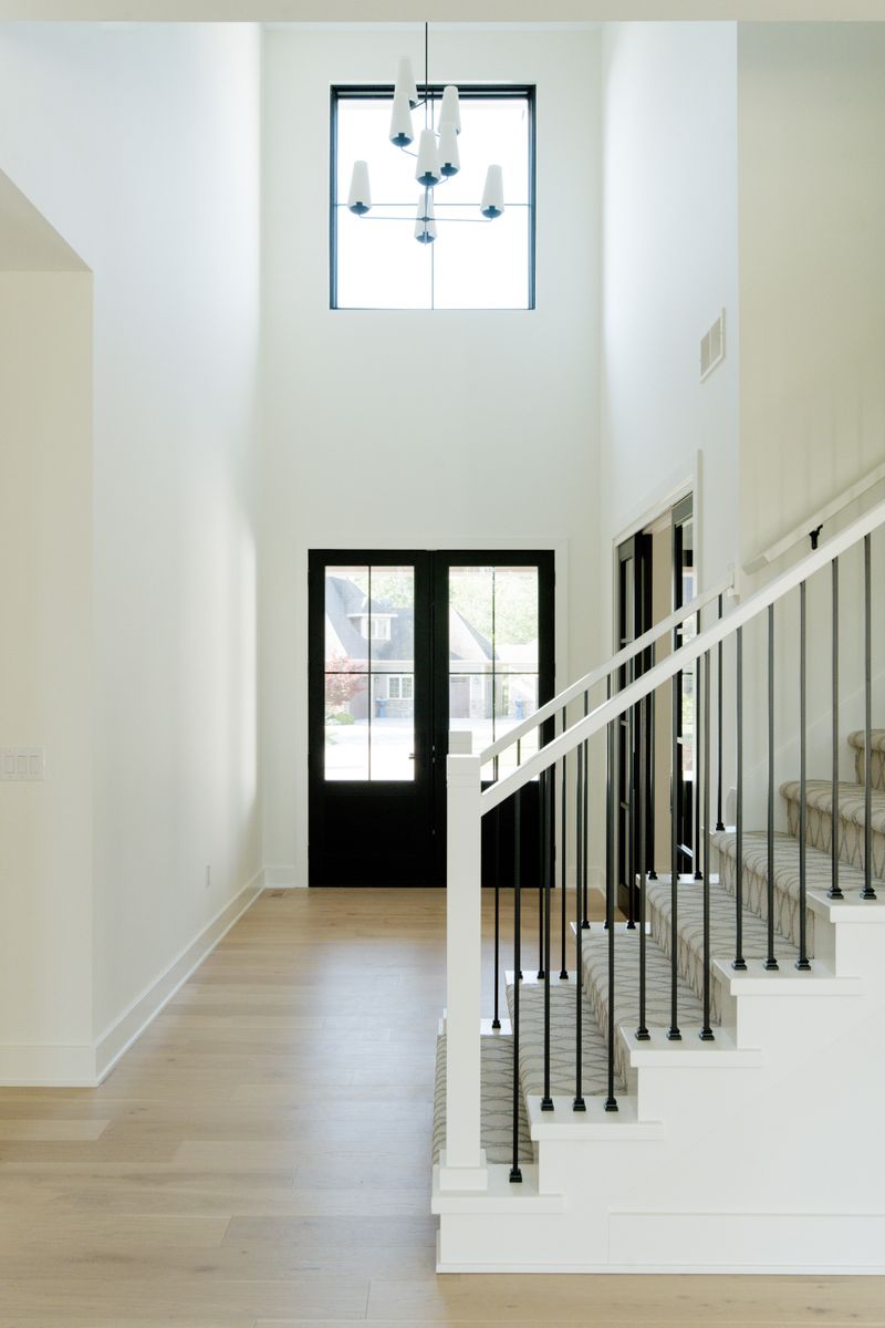A two story white entry in Waukee with black iron stair spindles and a patterned stair runner.