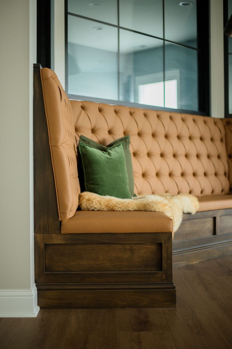 A dining nook in Van Meter with a tufted tan leather banquette built into a dark stained wood base.