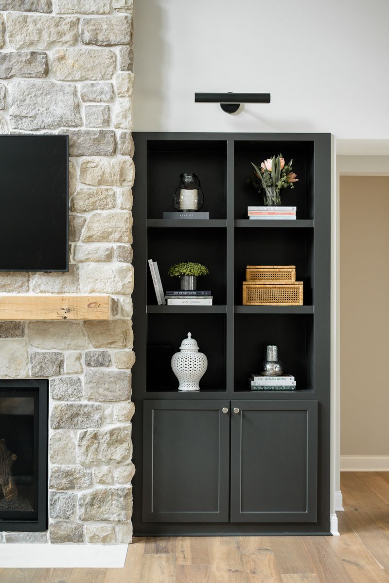 A living room in Van Meter with charcoal built-in shelving beside a limestone fireplace and rough wood mantel.