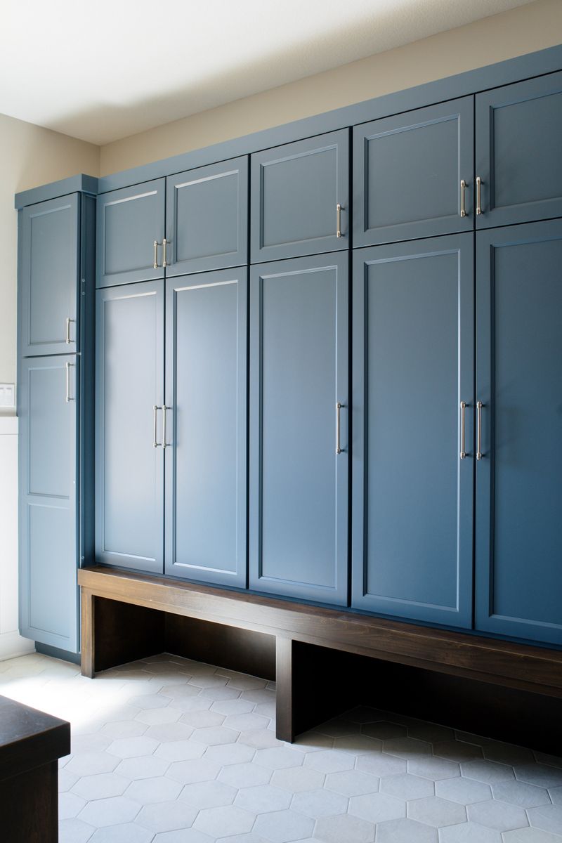 A blue mudroom in Van Meter with a dark stained wood bench running under floor to ceiling lockers.