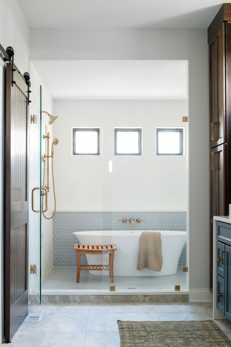 A primary bath in Van Meter with a freestanding tub set against blue hexagon tile and brass wall faucets.