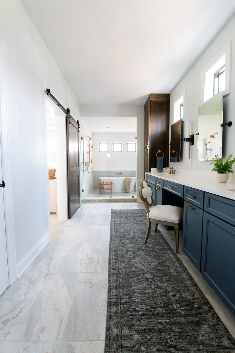 A primary bath in Van Meter with navy vanity cabinets and brass fixtures, opening to a wet room tub.