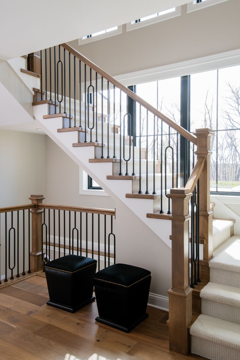 A stairwell in Van Meter with black iron balusters set against a stained oak handrail and newel post.