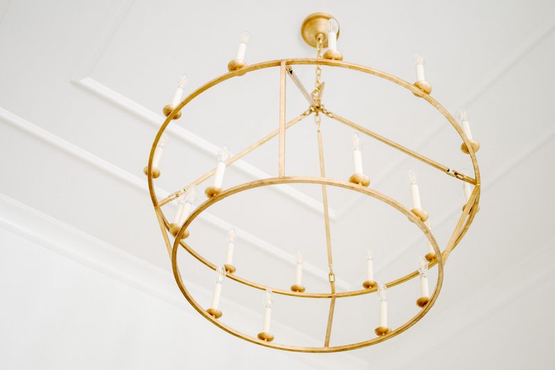 A two tier gold ring chandelier in Urbandale hanging against a white ceiling with layered trim.