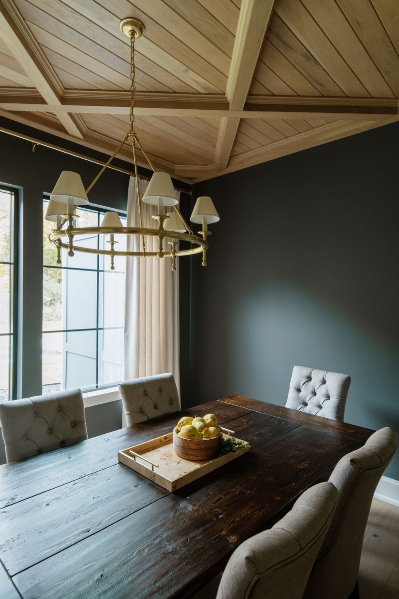 A dark green dining room in Urbandale with a brass ring chandelier under a white oak coffered ceiling.