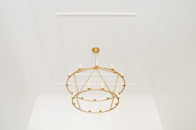 A two tier gold candle chandelier in an Urbandale entry, hung below a white coffered ceiling panel.