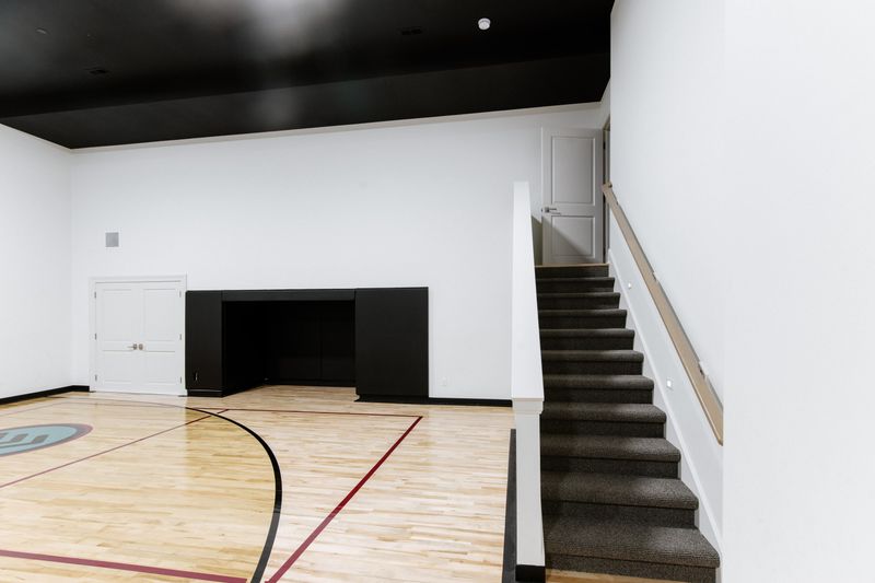 A home sport court in Urbandale with a maple floor and a black ceiling above the painted white walls.