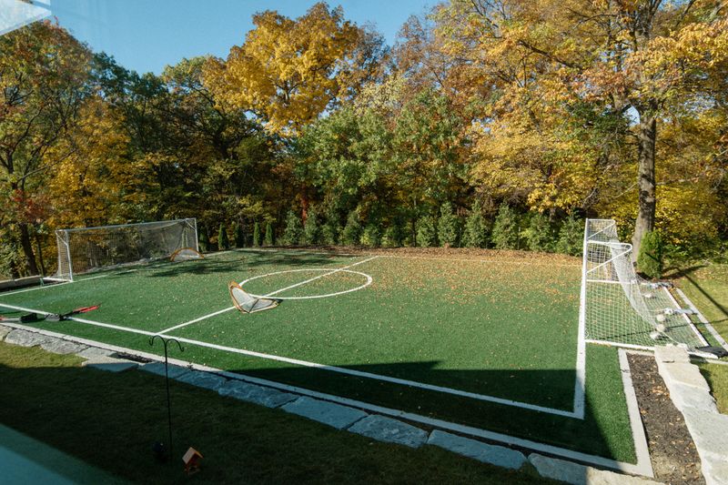 A backyard sport court in Urbandale with turf and a soccer goal edged by a stone border.
