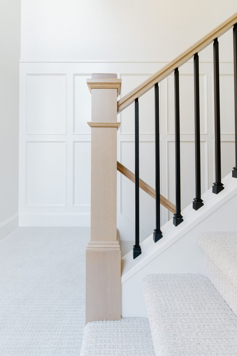 A white stairwell in Urbandale with a white oak newel post and black metal balusters.