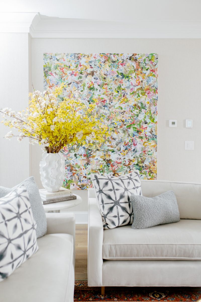 A cream living room in Des Moines with a large Jackie Hilmes original painting above white sofas.