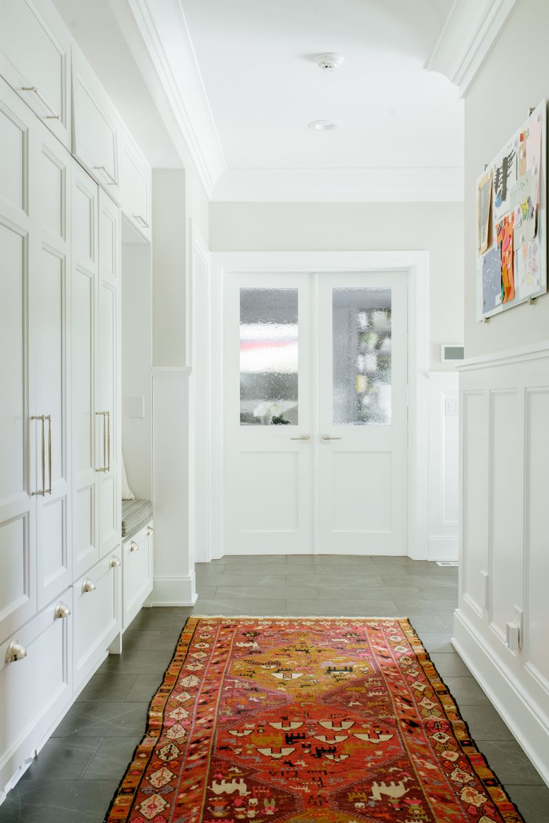 A white mudroom in Des Moines with a red patterned runner over gray slate tile floors.