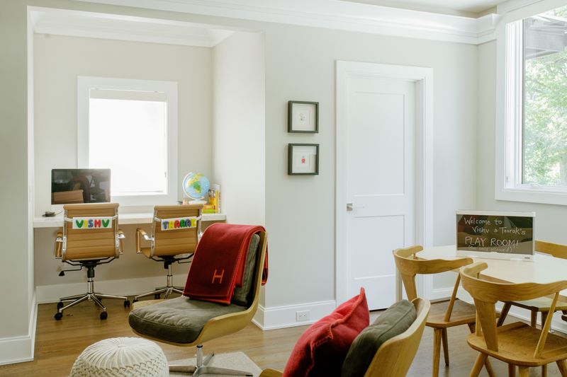 A white playroom in Des Moines with a light oak kids table and spindle chairs on wood floors.