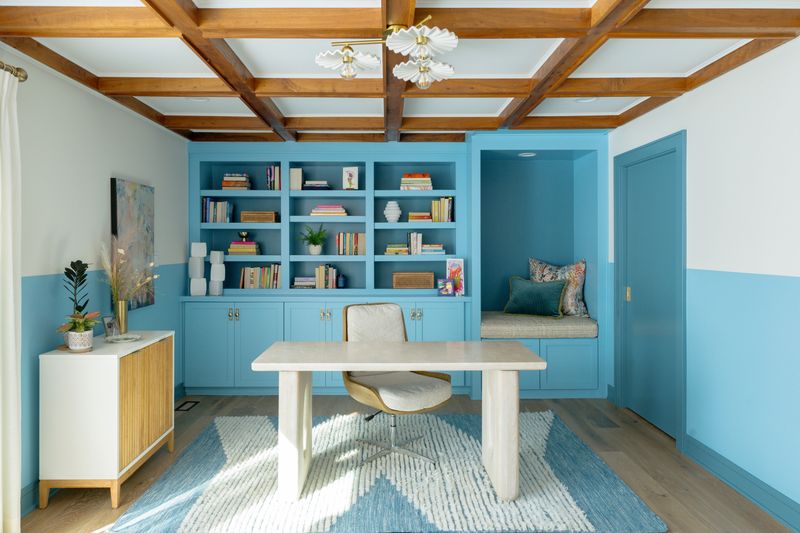 A blue home office in Des Moines with a built-in reading nook under wood beamed ceilings.