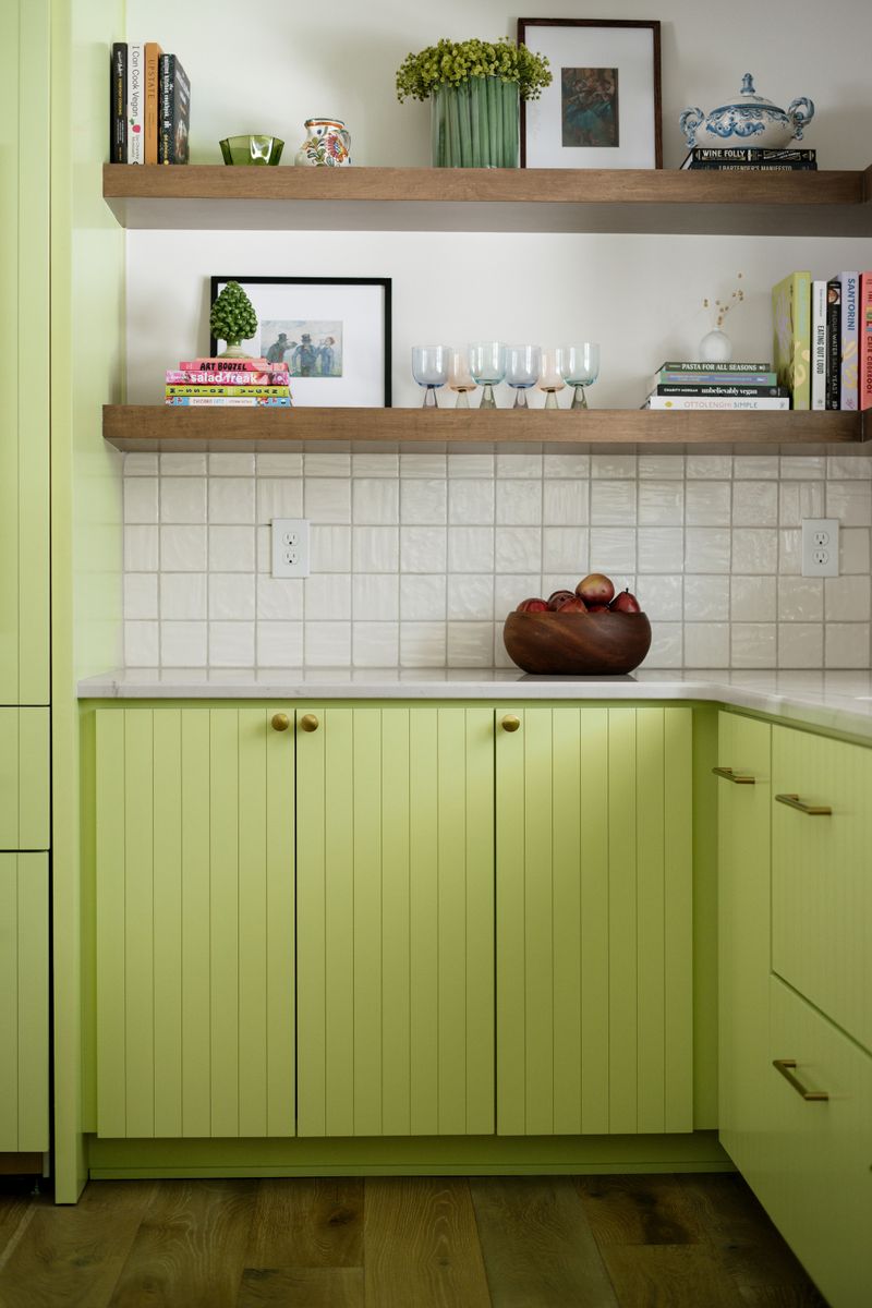 A Des Moines kitchen with lime green beadboard cabinets and brass knobs under a white square tile backsplash.