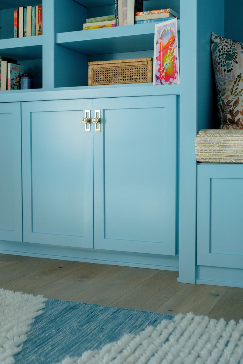 A living room in Des Moines with sky blue built-in cabinets and brass hardware above white oak floors.