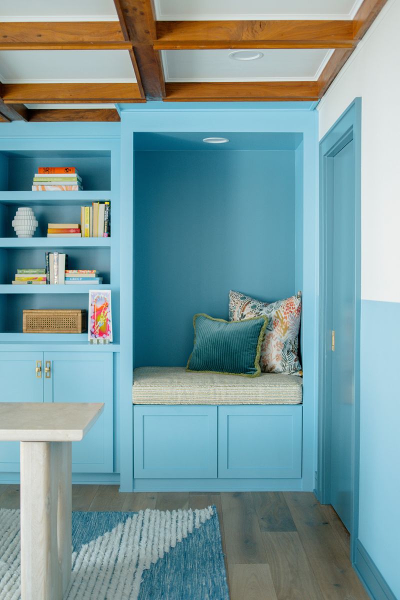 A living room in Des Moines with a blue built-in reading nook set under a wood beamed ceiling.