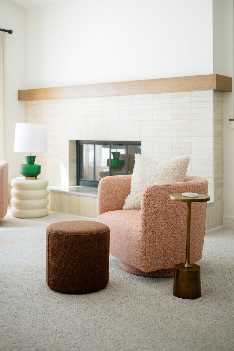A Des Moines living room with a terracotta swivel chair beside a cream tile fireplace under a wood mantel.