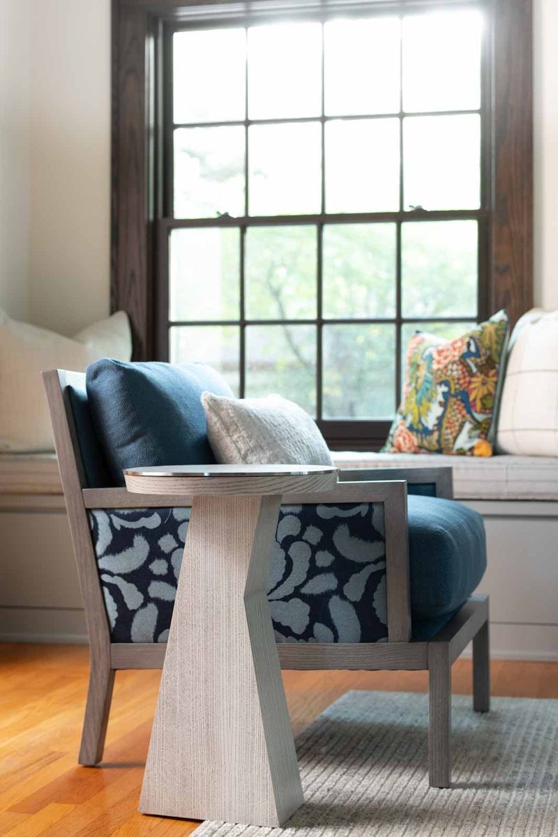 A Des Moines living room with a navy ikat armchair beside a built-in window seat under a dark wood window.