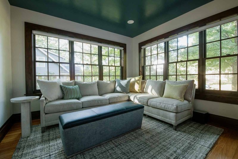 A living room in Des Moines with a glossy deep teal ceiling over a cream sectional in the window corner.