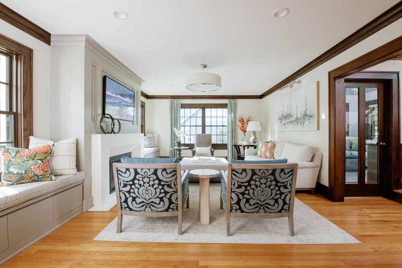 A living room in Des Moines with a built-in window seat beside a paneled greige fireplace surround.