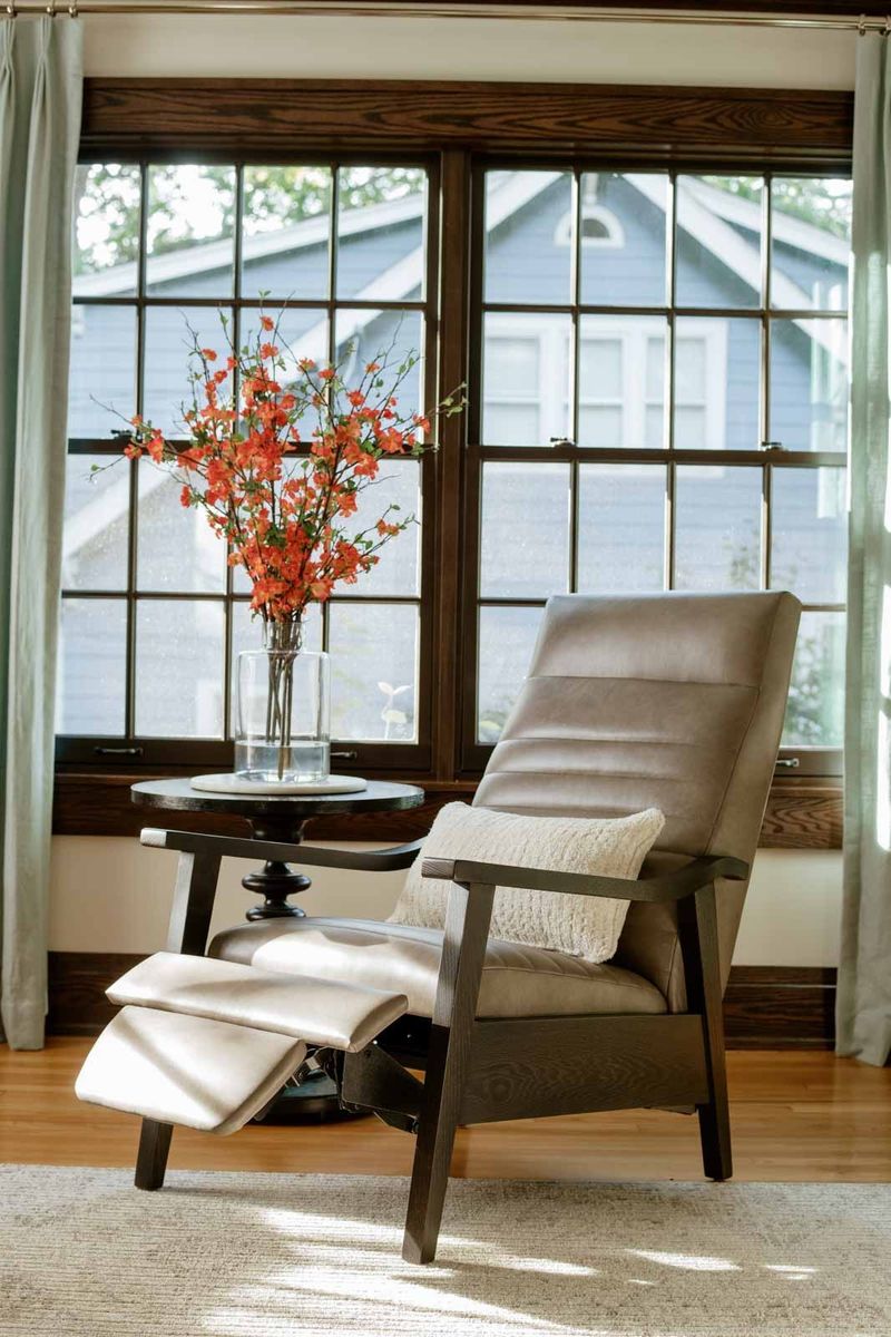 A living room in Des Moines with a gray leather recliner set against dark stained wood windows.