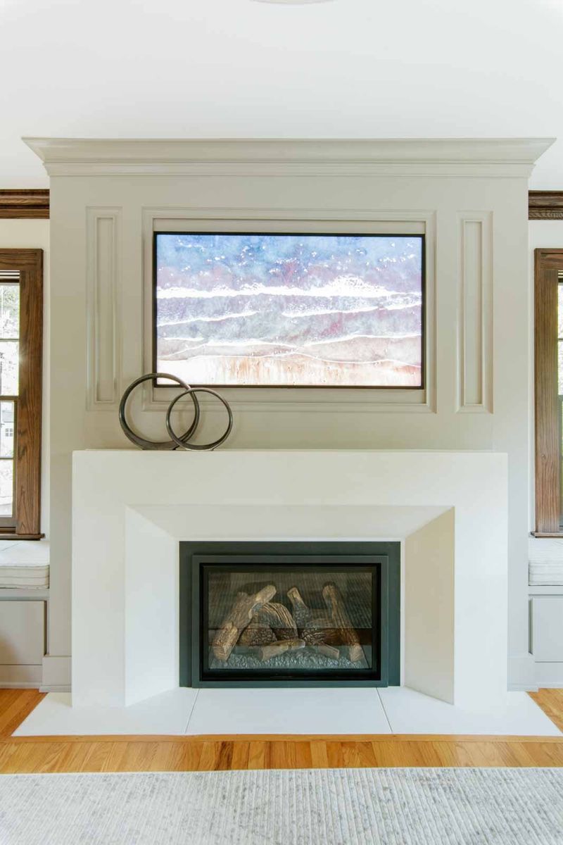 A living room in Des Moines with a white paneled fireplace surround and a recessed art screen above the mantel.