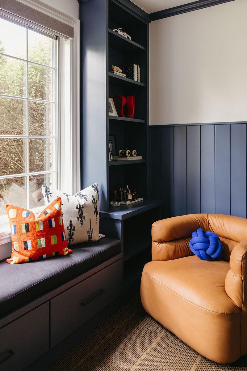 A navy bedroom in Clive with a built-in window seat and shelves beside vertical navy paneling.