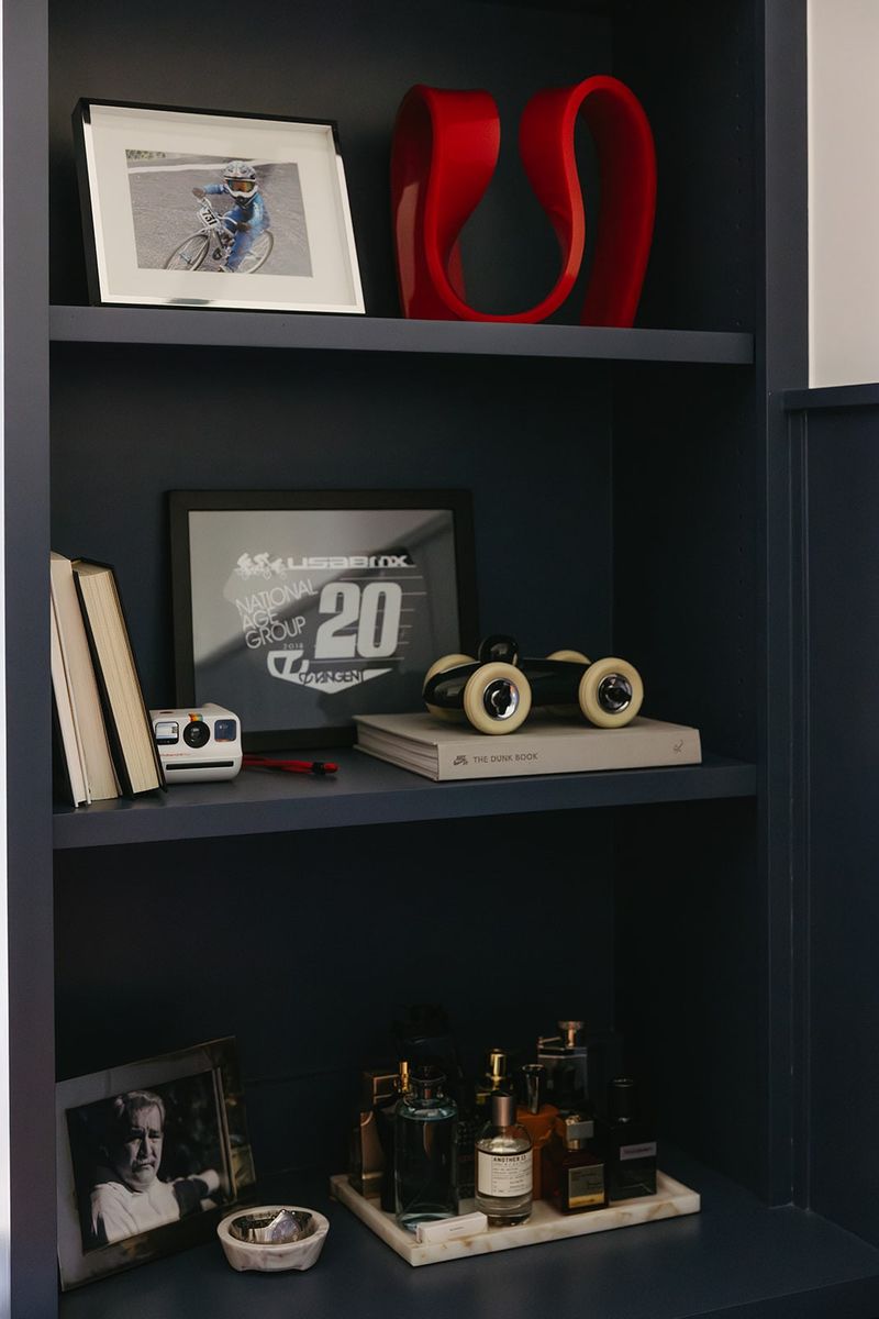 Navy blue built in shelves in Clive styled with a red sculpture and framed BMX racing art.