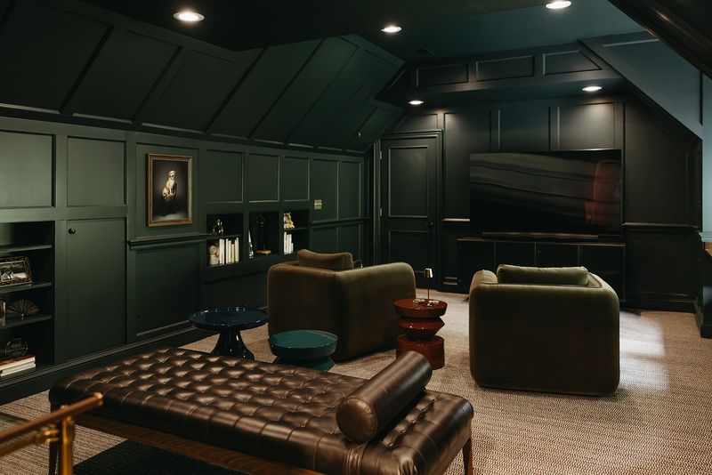 A media room in Clive with dark green paneled walls and olive lounge chairs on a woven sisal rug.