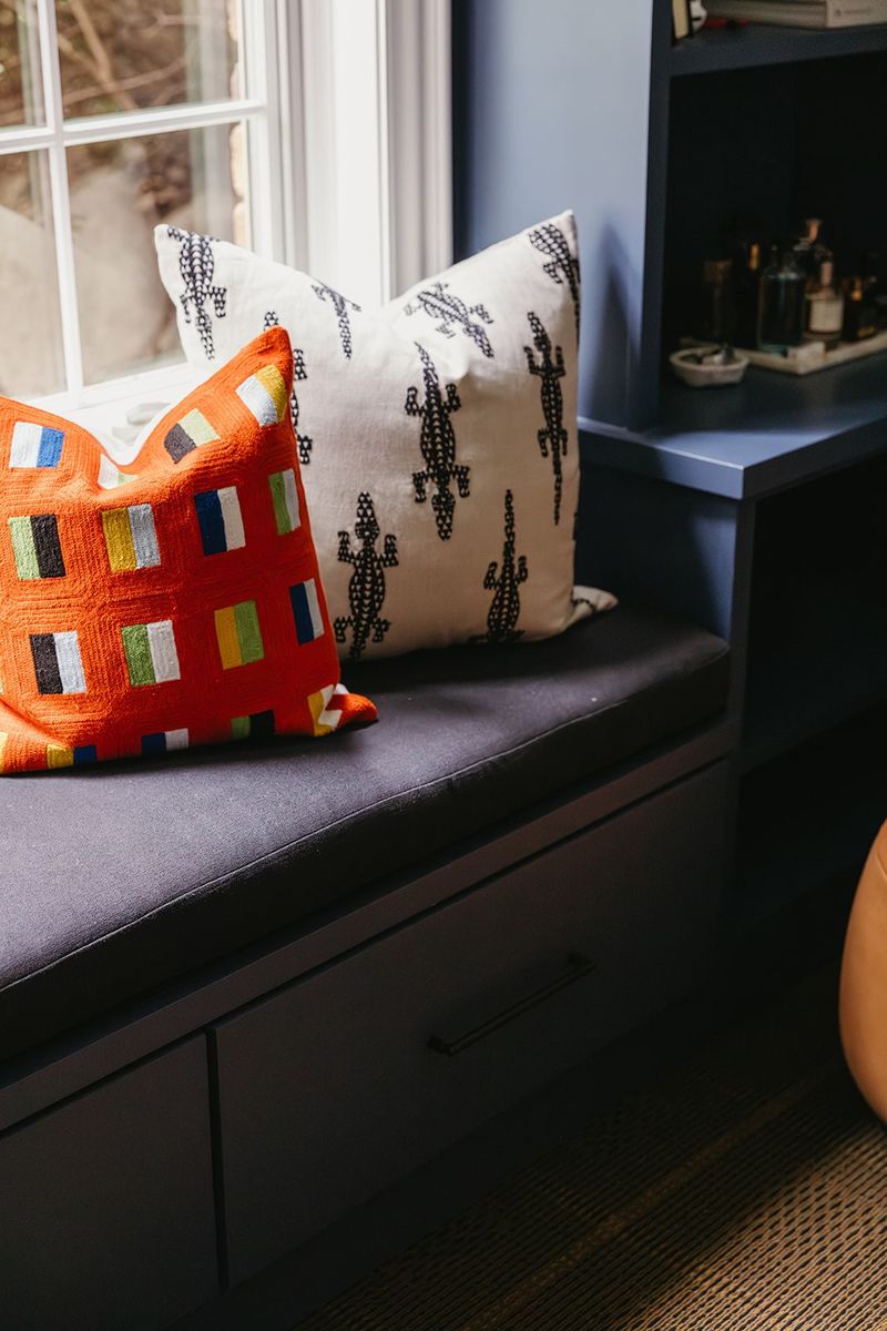 A navy office window seat in Clive with a built-in bench and an orange embroidered pillow.