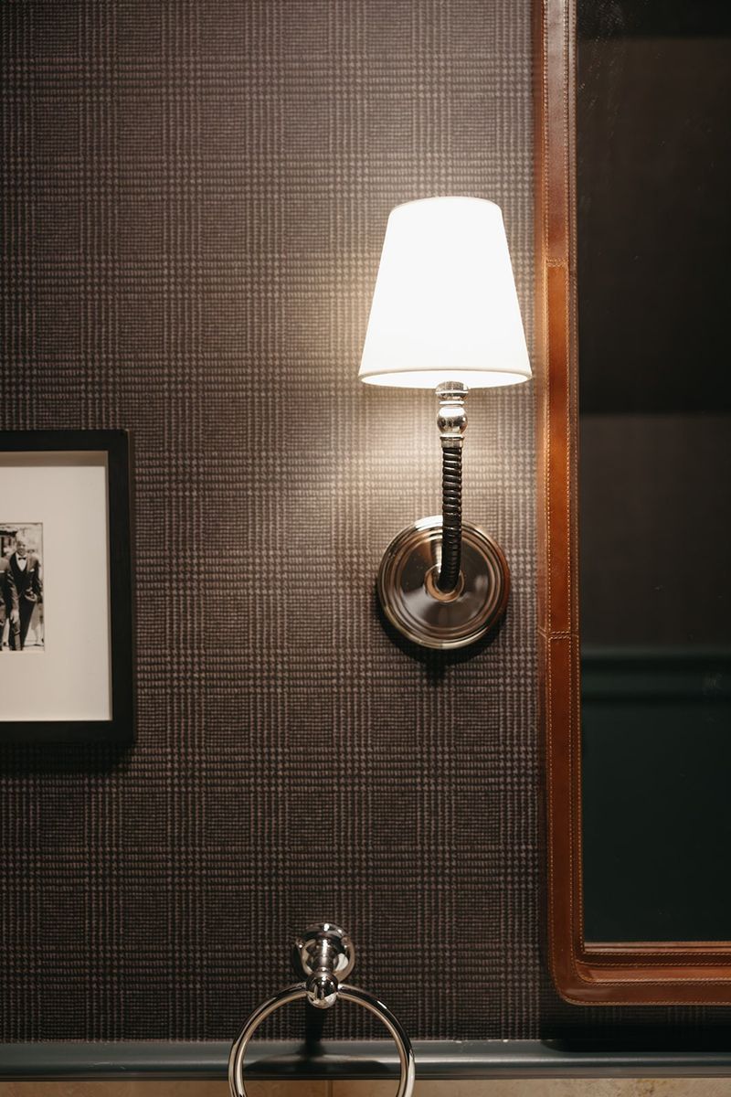 A brown plaid office wall in Clive with a nickel sconce beside a leather trimmed doorway.
