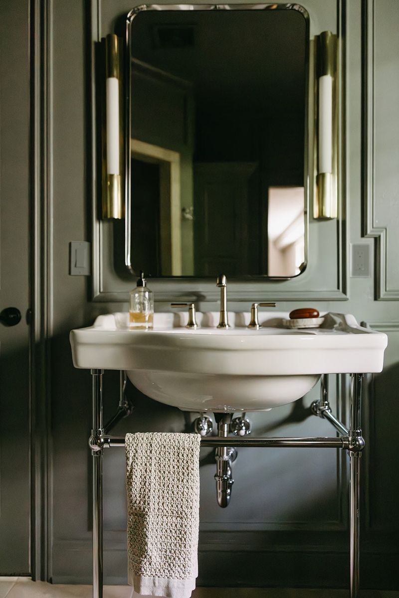 A dark green powder room in Clive with a white console sink on a polished chrome frame.