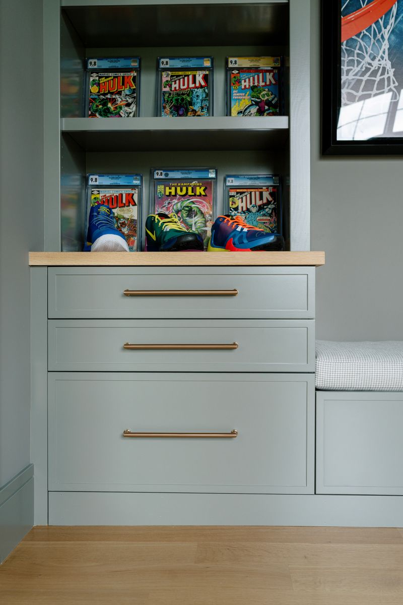 A kid's bedroom in West Des Moines with sage green built-in drawers, brass pulls and a white oak top.