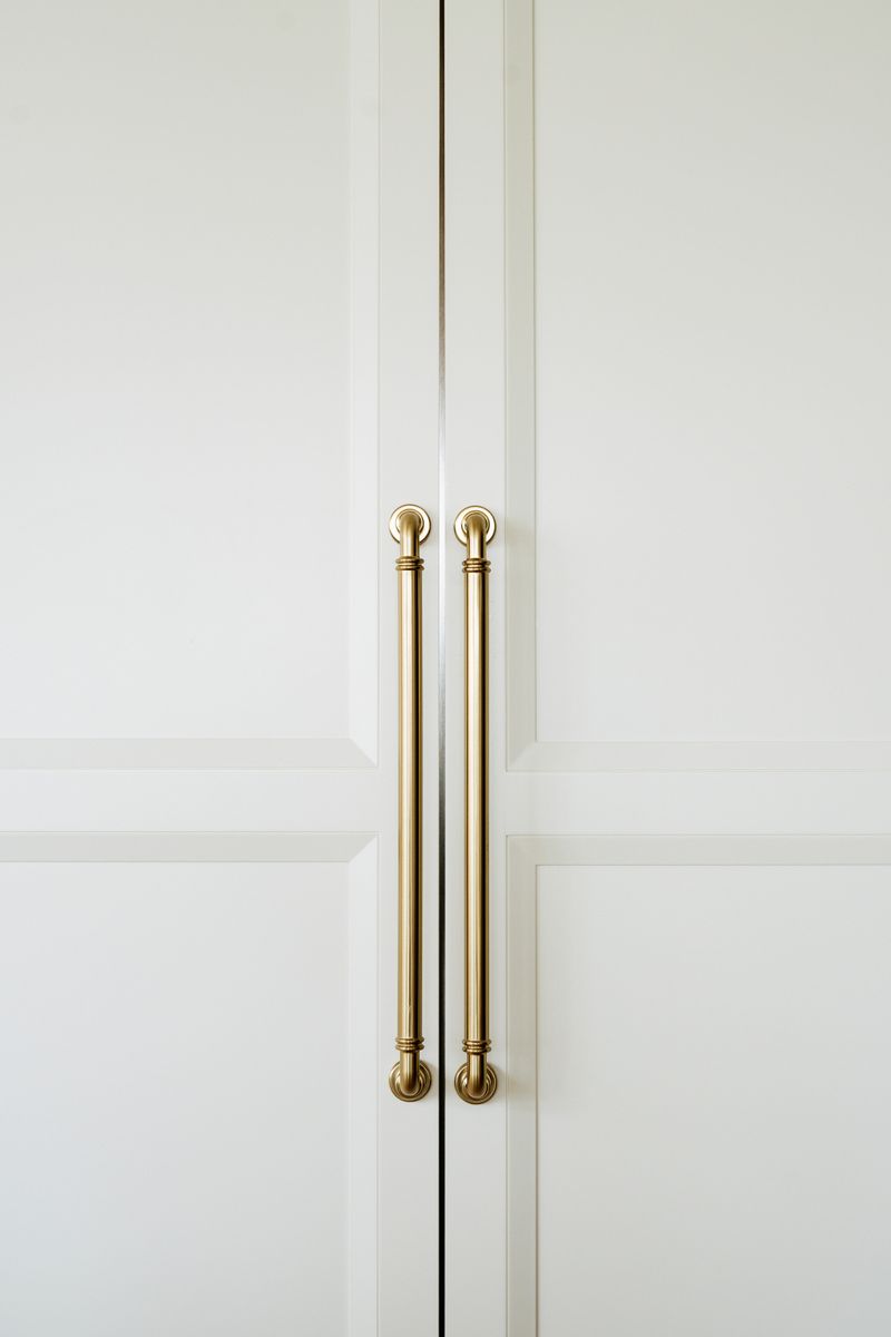 Long brass pulls on white paneled cabinet doors in a West Des Moines kitchen.